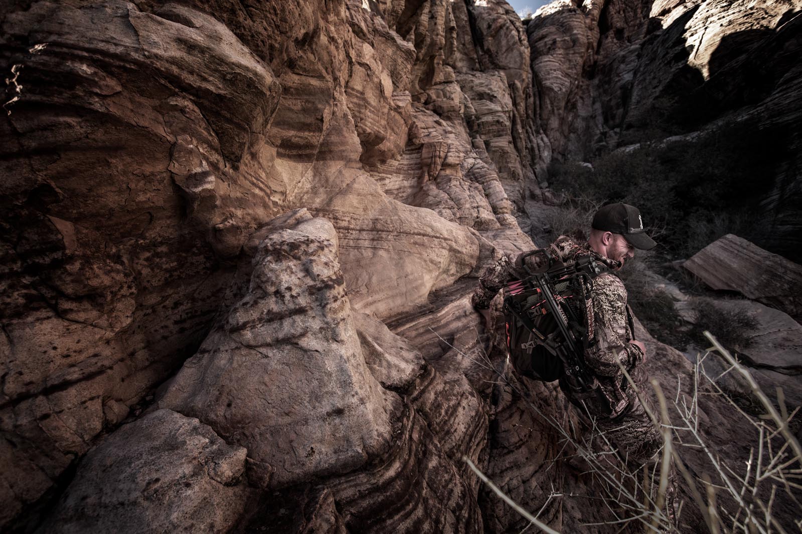 Man wearing gear climbing into a canyon after retouching